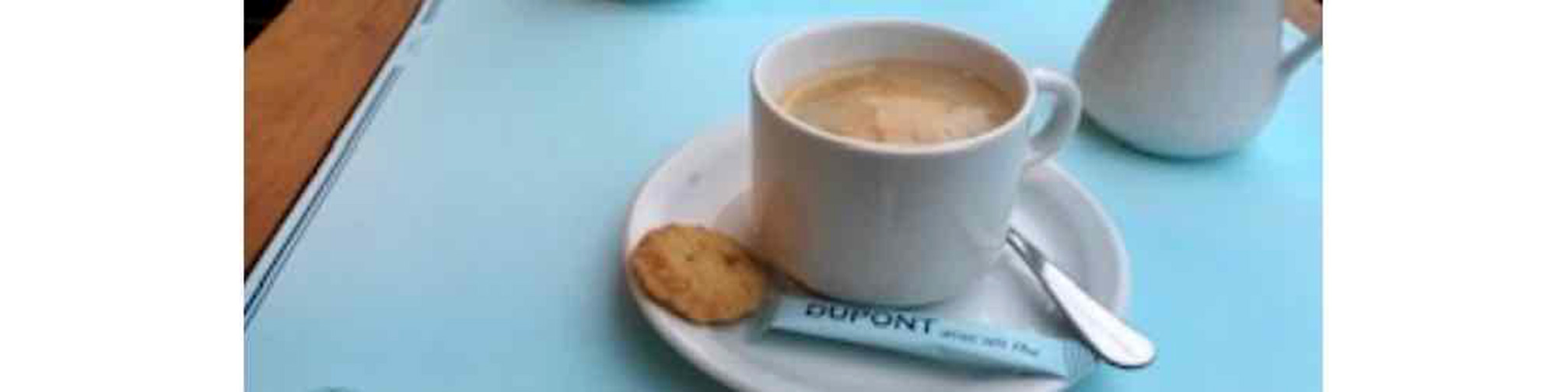 cup of coffee with small biscuit and spoon on saucer