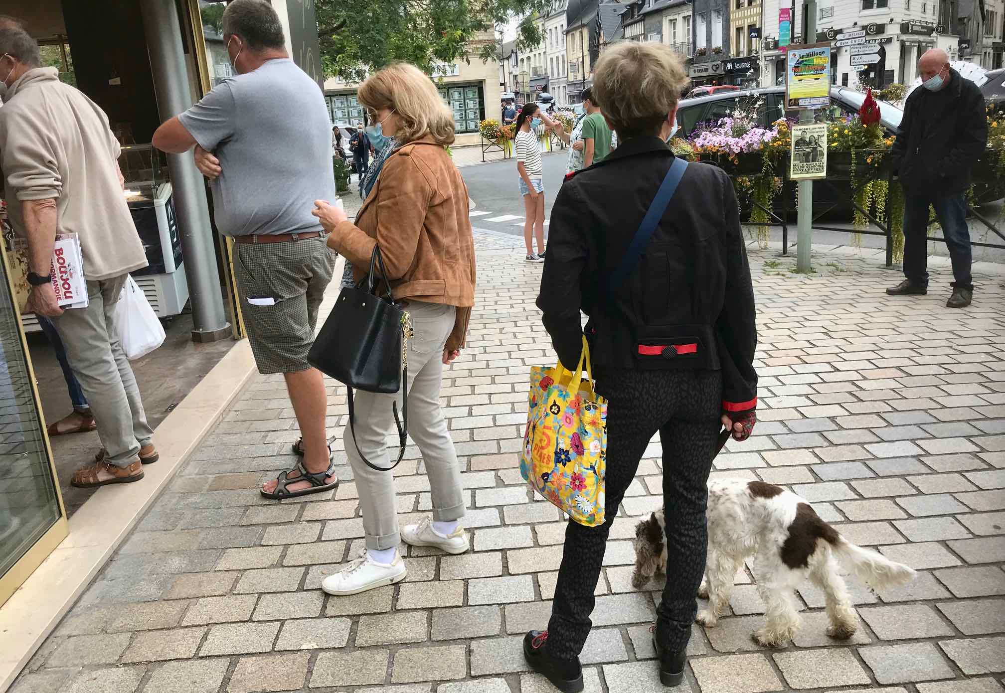 shoppers lined up at French shop wearing masks and social distacing,