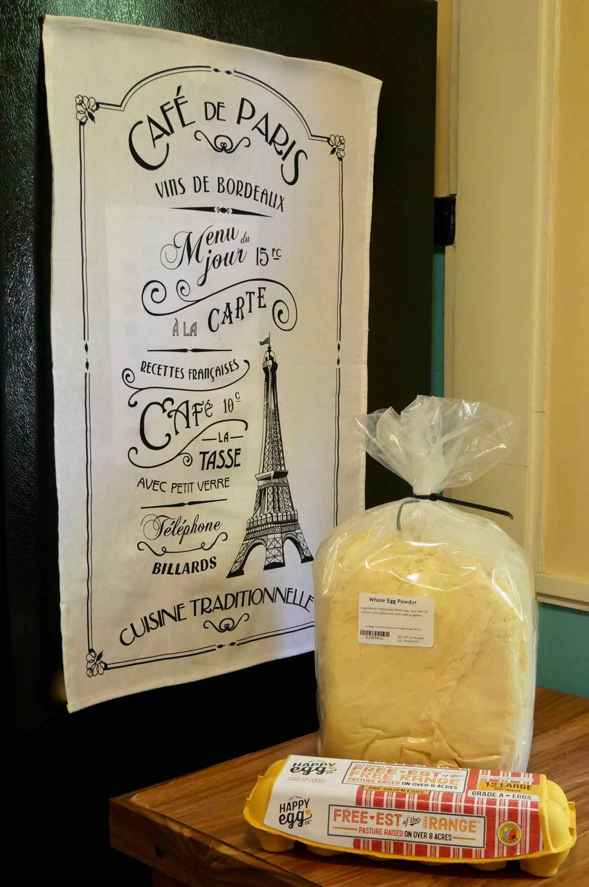 10 pound bag of 400 powdered whole eggs sitting next to a standard-sized carton for 1 dozen eggs
